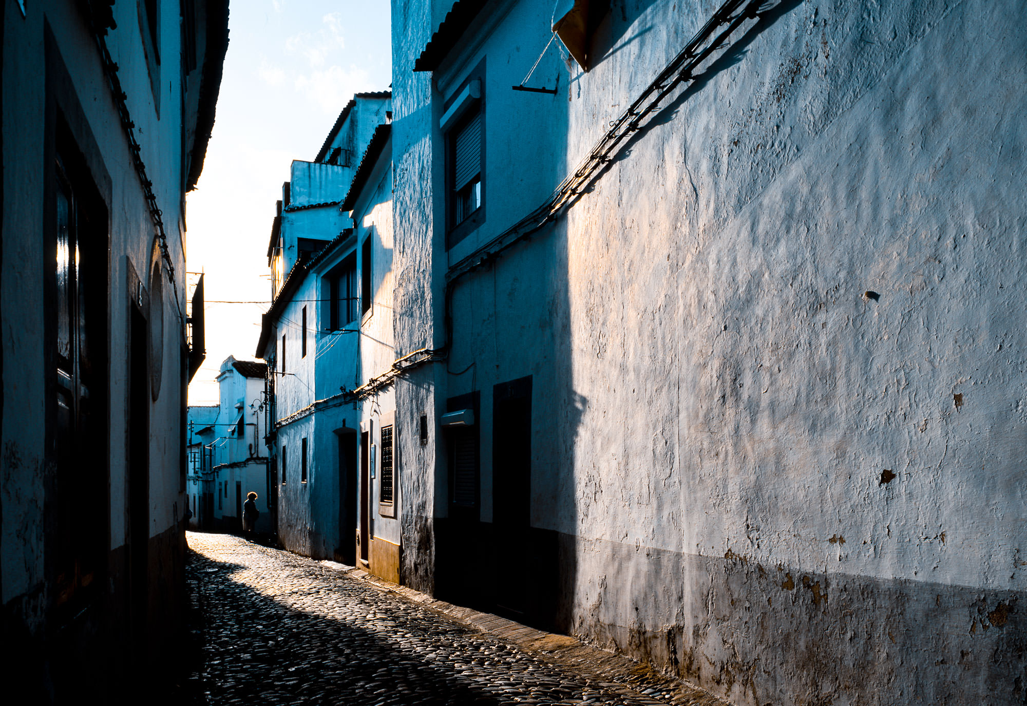 Photograph of Evora, Portugal in the early morning.  An old cobblestone alley.