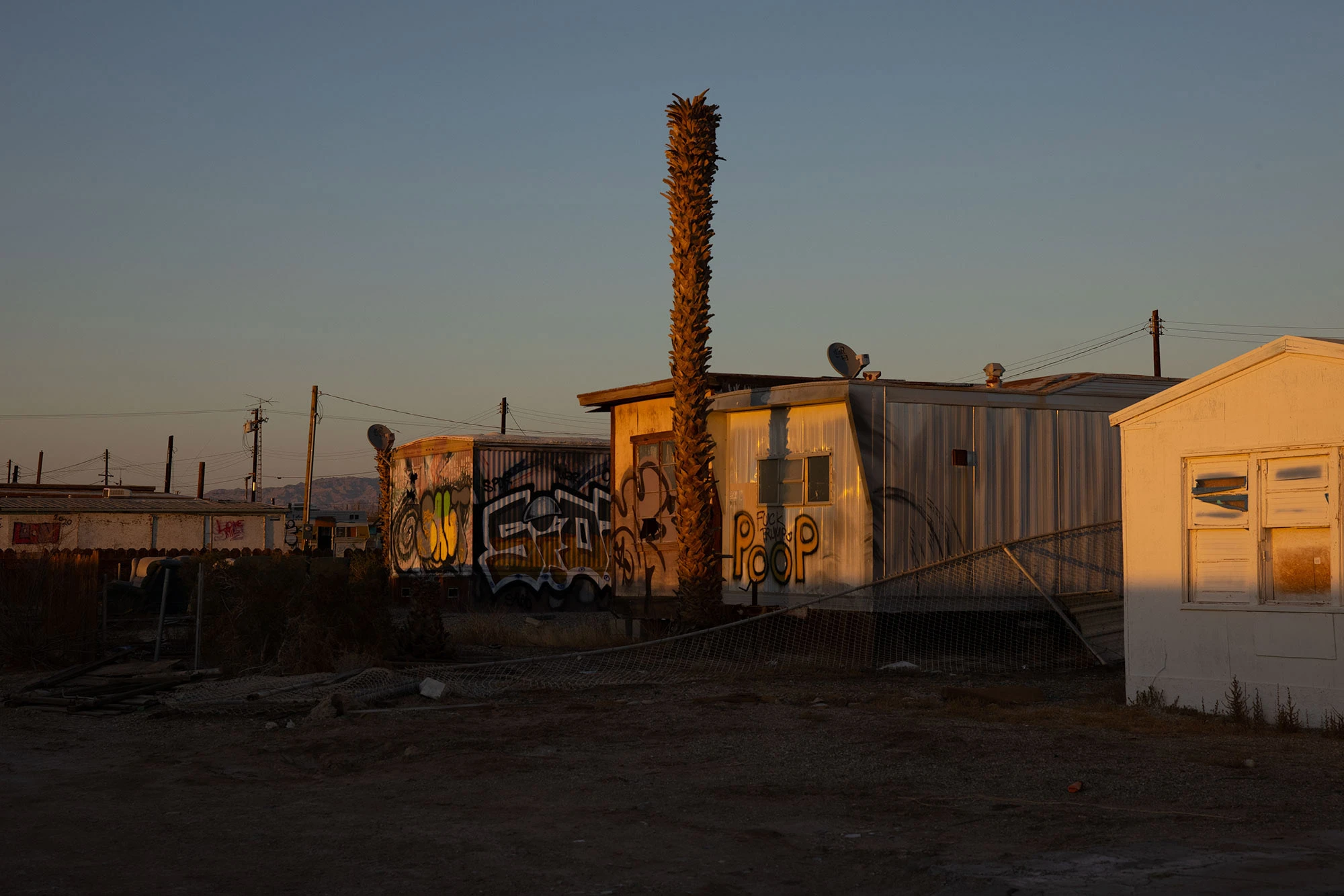Graffiti-covered derelict buildings at Bombay Beach on California's Salton Sea, their crumbling walls transformed into canvases for outsider art amid the ruins of a once-thriving resort town.